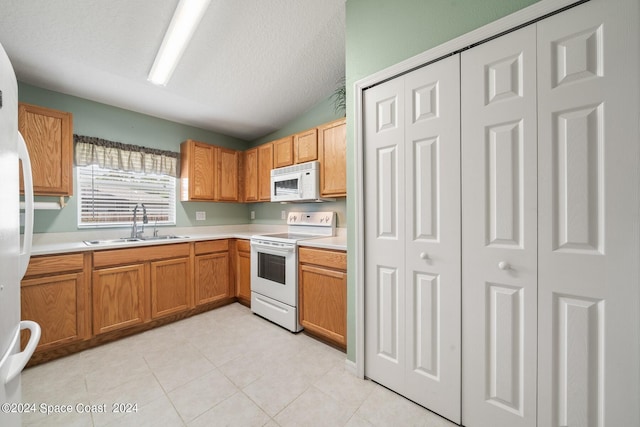 kitchen with white appliances, a textured ceiling, light tile patterned floors, sink, and vaulted ceiling