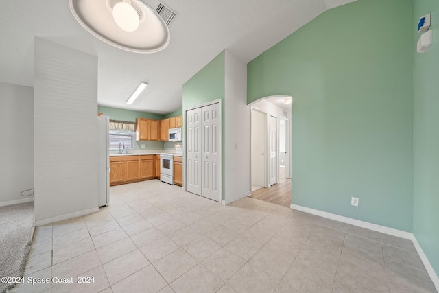 kitchen with vaulted ceiling, light tile patterned floors, and white appliances