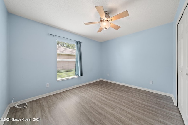 unfurnished room with a textured ceiling, wood-type flooring, and ceiling fan