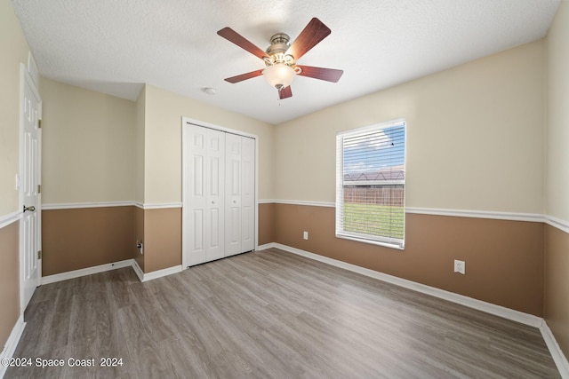 unfurnished bedroom with a textured ceiling, light hardwood / wood-style flooring, ceiling fan, and a closet