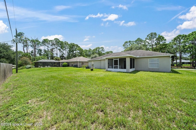 rear view of house with a sunroom and a yard