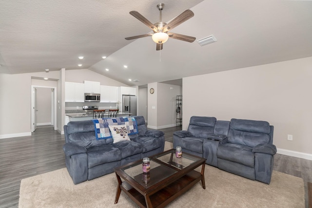 living room featuring lofted ceiling, ceiling fan, wood-type flooring, and a textured ceiling