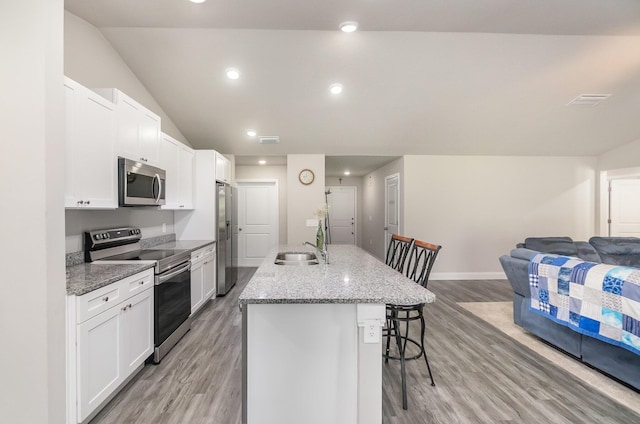 kitchen with stainless steel appliances, an island with sink, a breakfast bar, and white cabinets