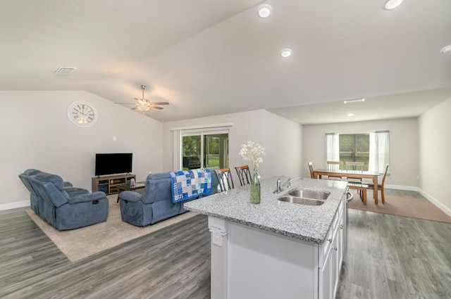 kitchen featuring sink, hardwood / wood-style flooring, a kitchen island with sink, white cabinets, and vaulted ceiling