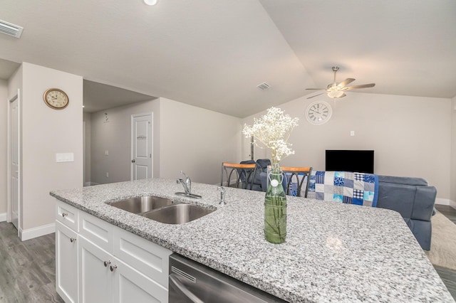 kitchen with sink, white cabinetry, light stone counters, wood-type flooring, and stainless steel dishwasher