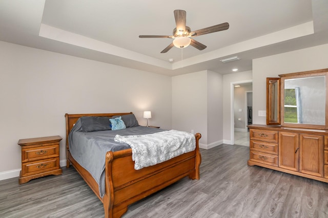 bedroom featuring a tray ceiling, ceiling fan, and hardwood / wood-style flooring