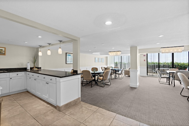 kitchen with light tile patterned flooring, white cabinets, pendant lighting, and an inviting chandelier