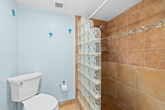 bathroom with tile patterned flooring, toilet, and tiled shower