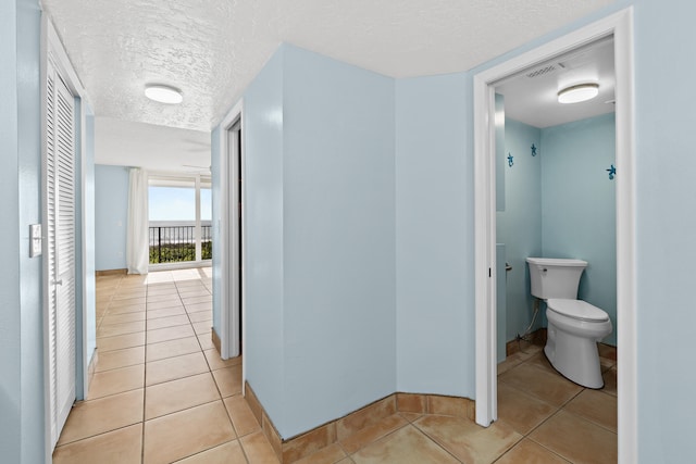 hallway featuring light tile patterned floors and a textured ceiling