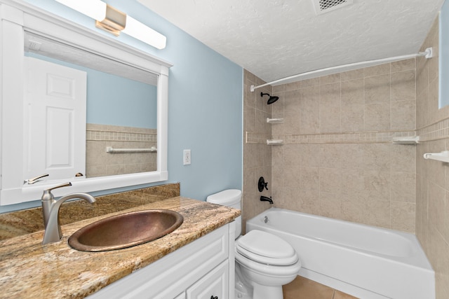 full bathroom featuring vanity, tile patterned flooring, tiled shower / bath combo, toilet, and a textured ceiling