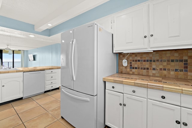 kitchen with tile countertops, white appliances, white cabinets, tasteful backsplash, and light tile patterned flooring