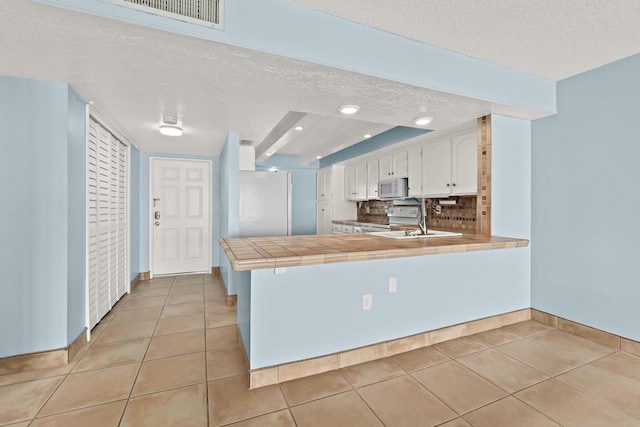 kitchen featuring tile countertops, white appliances, light tile patterned floors, and white cabinets