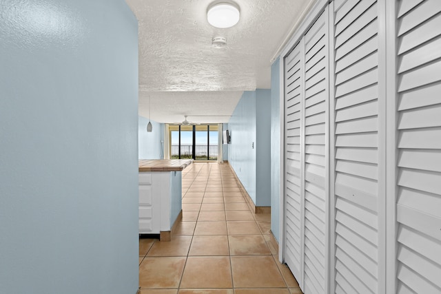 corridor featuring light tile patterned floors and a textured ceiling