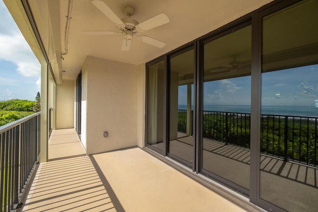 balcony with a water view and a ceiling fan