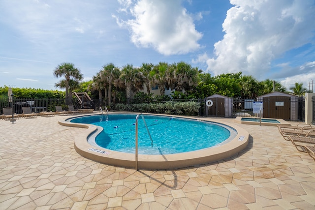 view of pool featuring a patio area, a jacuzzi, and a shed