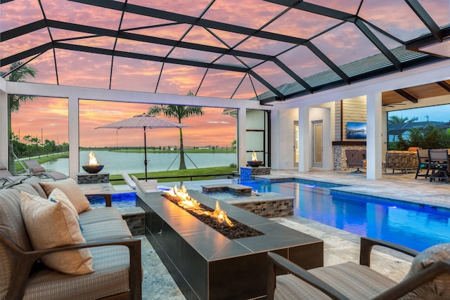 pool at dusk featuring glass enclosure, exterior bar, a patio area, and an outdoor living space with a fire pit