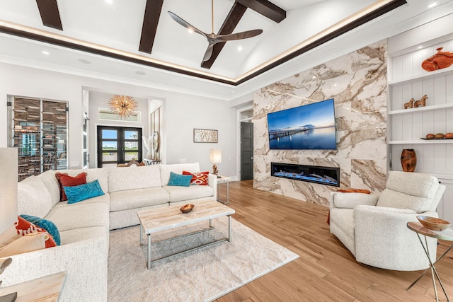 living room with high vaulted ceiling, ceiling fan, french doors, light hardwood / wood-style flooring, and a premium fireplace