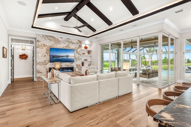 living room with built in shelves, light wood-type flooring, ceiling fan, beam ceiling, and a premium fireplace