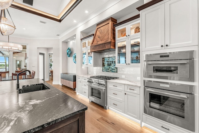 kitchen featuring stainless steel appliances, sink, white cabinets, decorative backsplash, and decorative light fixtures