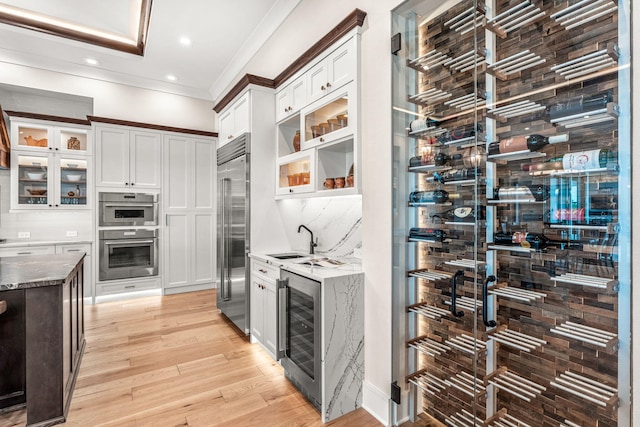 kitchen with wine cooler, stainless steel appliances, light hardwood / wood-style flooring, and white cabinetry