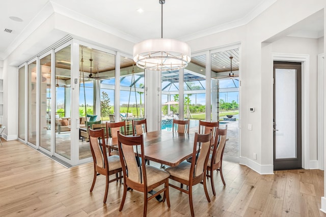 dining room featuring light wood-type flooring, french doors, ceiling fan with notable chandelier, and ornamental molding