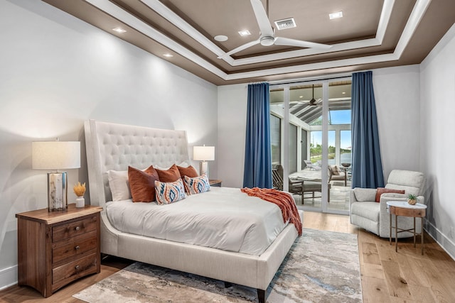 bedroom featuring a raised ceiling, crown molding, access to outside, and light wood-type flooring