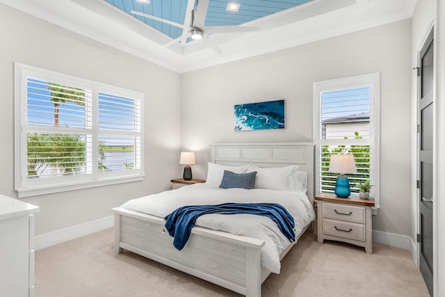 bedroom featuring ceiling fan, multiple windows, and light colored carpet