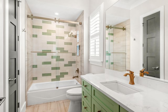 full bathroom with crown molding, toilet, hardwood / wood-style floors, tiled shower / bath, and vanity