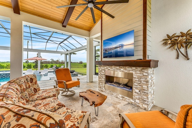 sunroom / solarium featuring ceiling fan, vaulted ceiling with beams, a stone fireplace, and wood ceiling