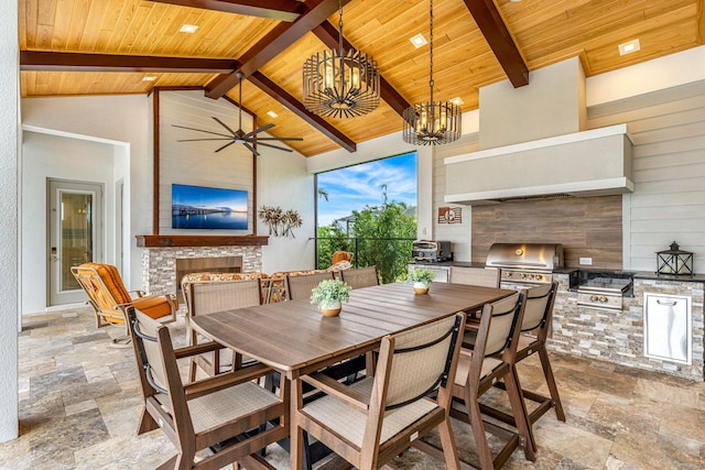 dining area with an outdoor fireplace, ceiling fan with notable chandelier, wood ceiling, beam ceiling, and tile patterned flooring