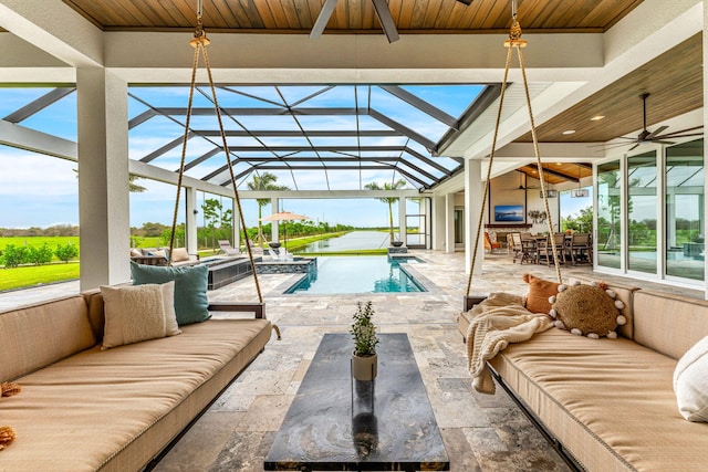 view of pool with glass enclosure, ceiling fan, outdoor lounge area, and a patio area