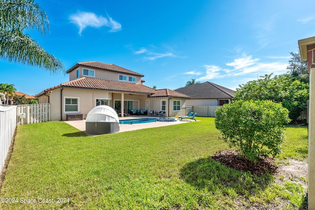 rear view of house featuring a lawn, a patio, and a fenced in pool