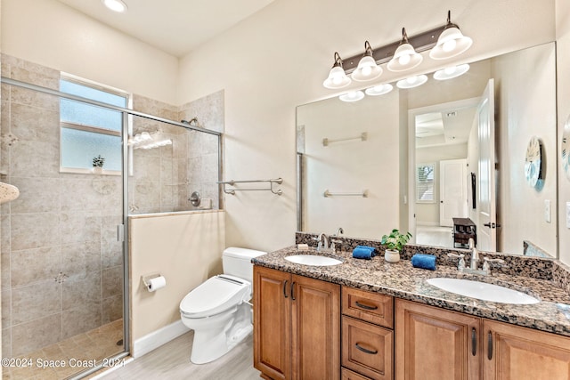 bathroom featuring wood-type flooring, walk in shower, vanity, and toilet