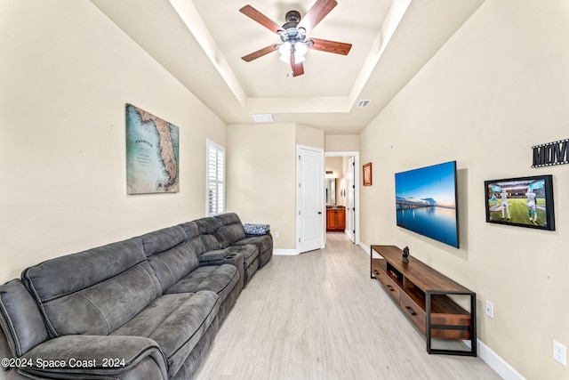 living room with ceiling fan, light hardwood / wood-style flooring, and a raised ceiling