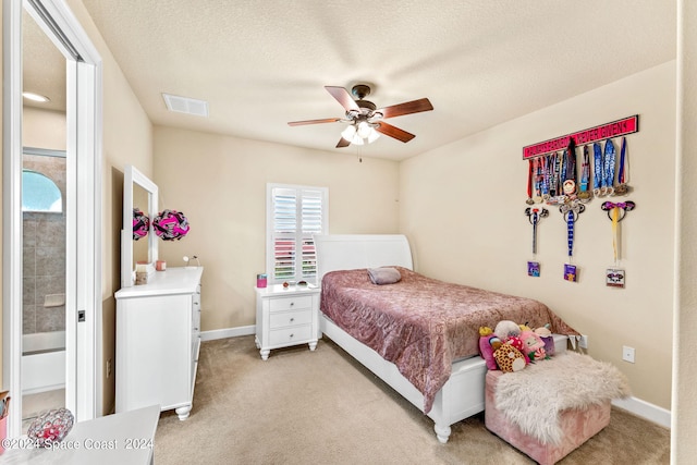 bedroom with a textured ceiling, ceiling fan, and light colored carpet