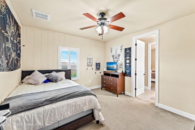 bedroom featuring ceiling fan, light colored carpet, and a textured ceiling