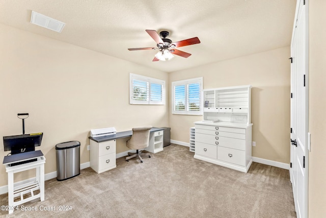 carpeted home office featuring a textured ceiling and ceiling fan