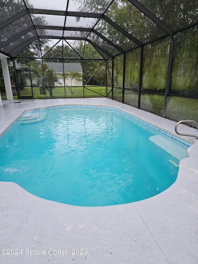 view of swimming pool featuring glass enclosure and a patio area