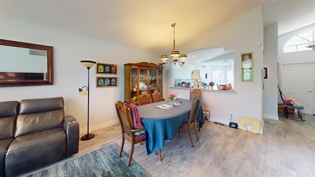 dining room with lofted ceiling, a textured ceiling, hardwood / wood-style flooring, and a chandelier