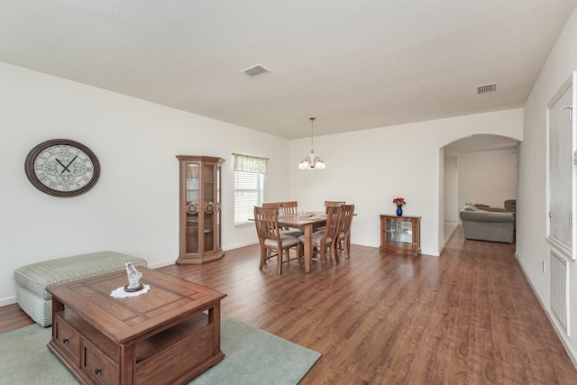 dining room featuring a textured ceiling, dark hardwood / wood-style flooring, and an inviting chandelier