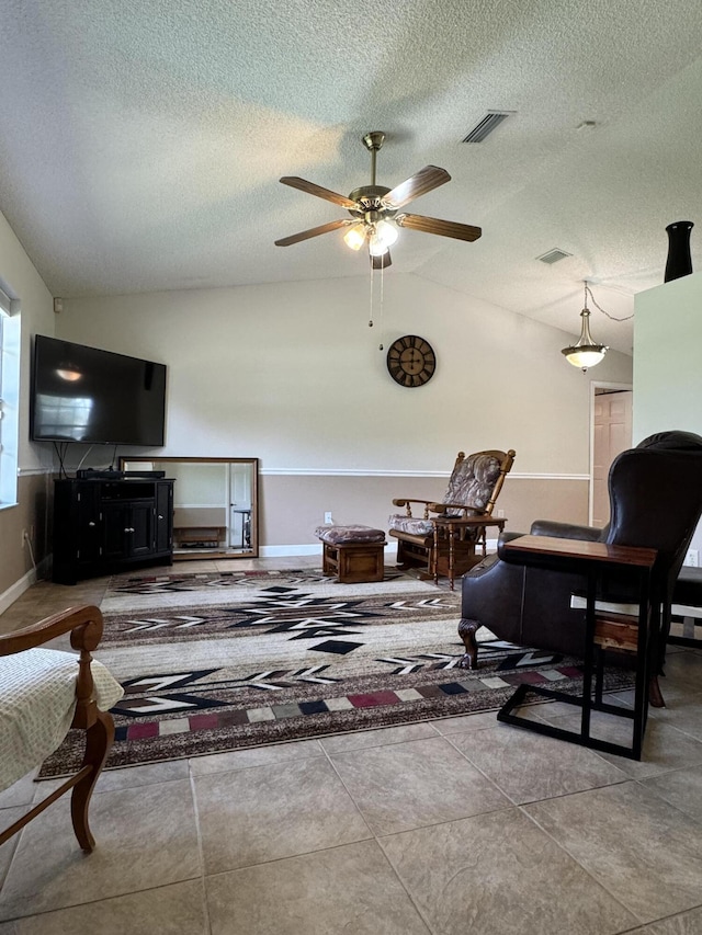 living room featuring ceiling fan, a textured ceiling, and tile patterned floors