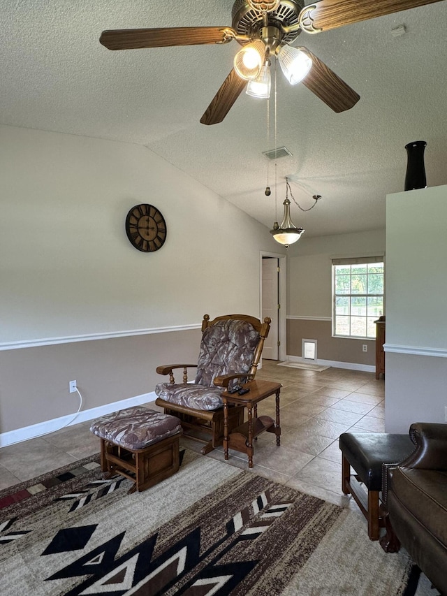 living area with a textured ceiling, ceiling fan, light tile patterned floors, and lofted ceiling