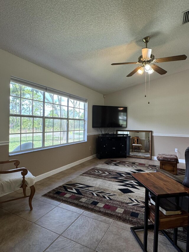 tiled living room with a textured ceiling and ceiling fan