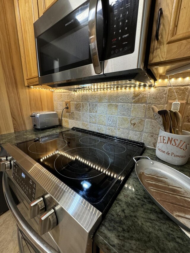 kitchen featuring backsplash, stainless steel appliances, and dark stone counters