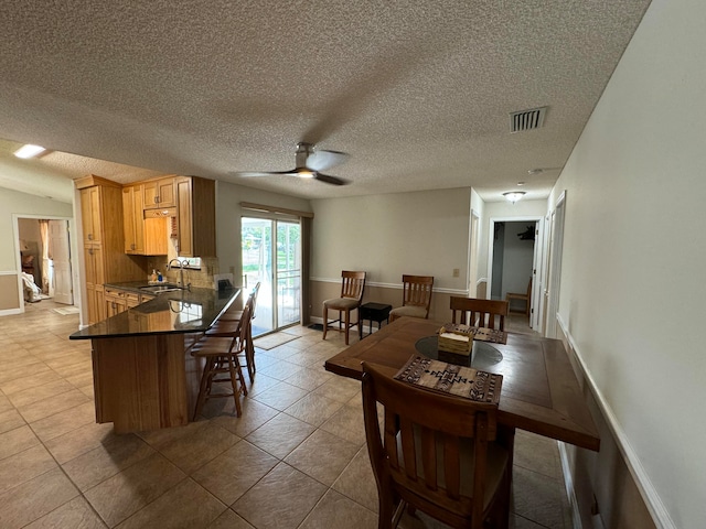 dining space featuring tile patterned flooring, ceiling fan, a textured ceiling, and sink