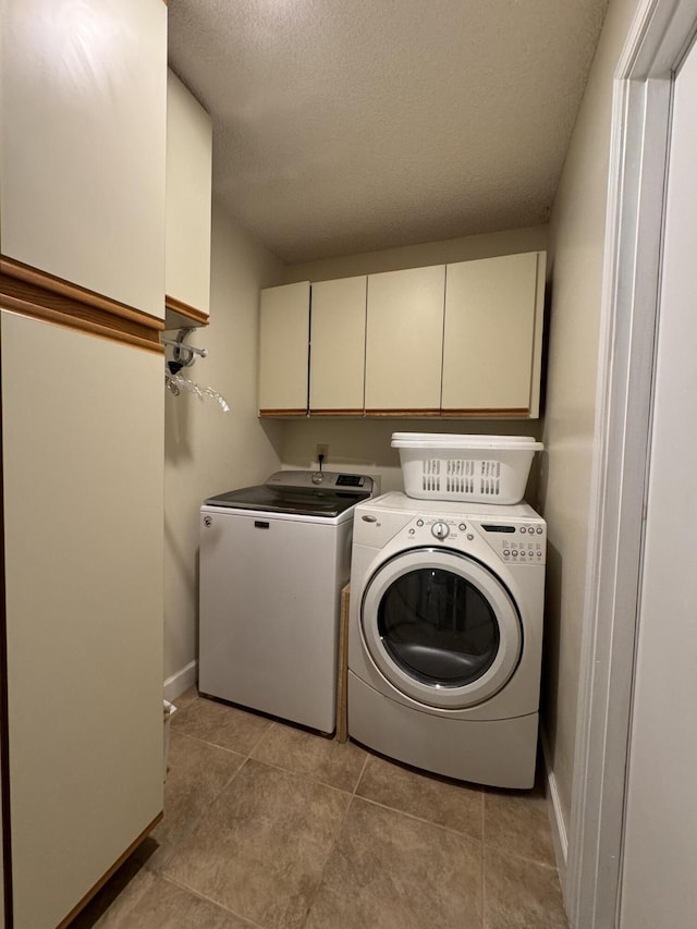 laundry area featuring washing machine and dryer, a textured ceiling, cabinets, and light tile patterned floors