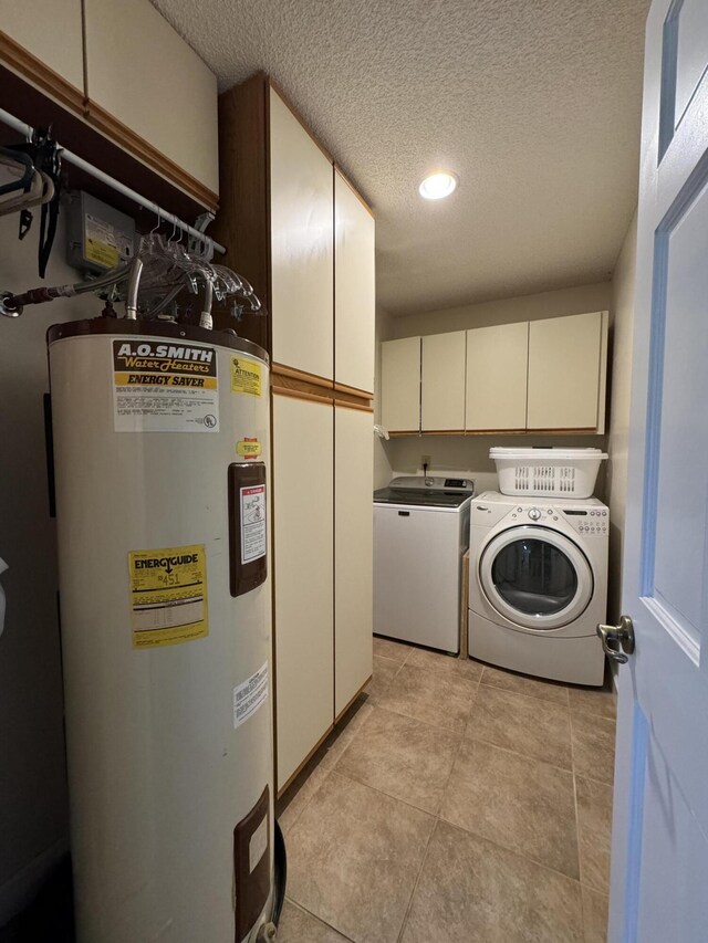 laundry area with separate washer and dryer, cabinets, electric water heater, a textured ceiling, and light tile patterned flooring