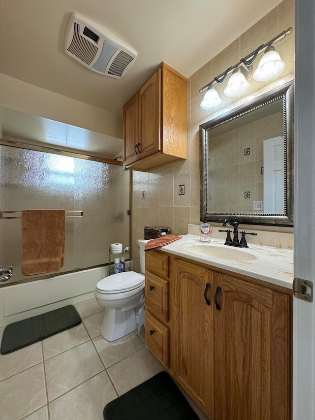 full bathroom with tile patterned floors, enclosed tub / shower combo, vanity, tile walls, and toilet