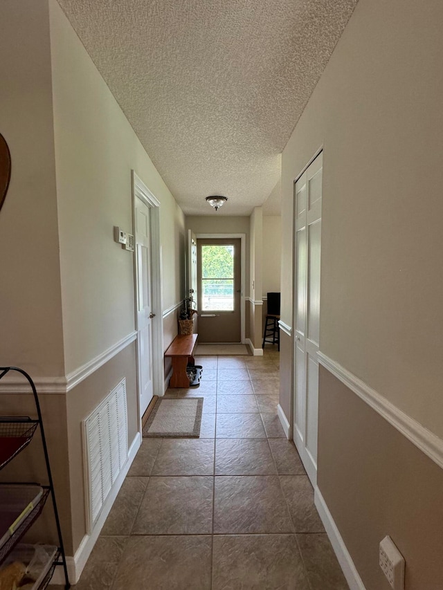 corridor featuring a textured ceiling and tile patterned floors