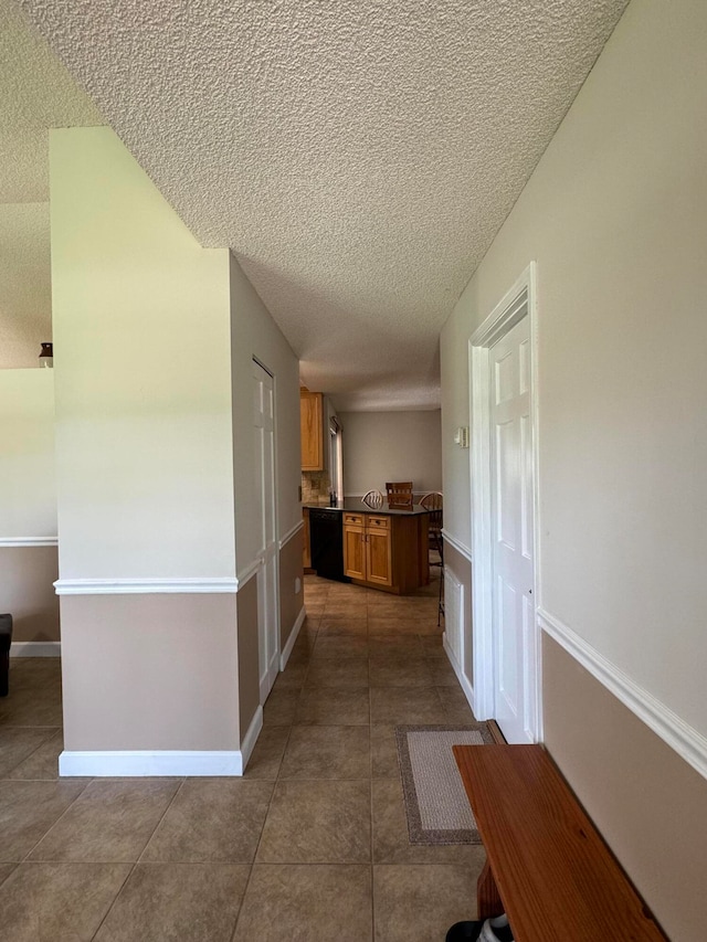 hall featuring tile patterned flooring and a textured ceiling